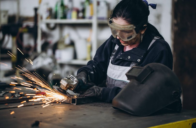 Eine junge mit Schutzbrille schweißt.